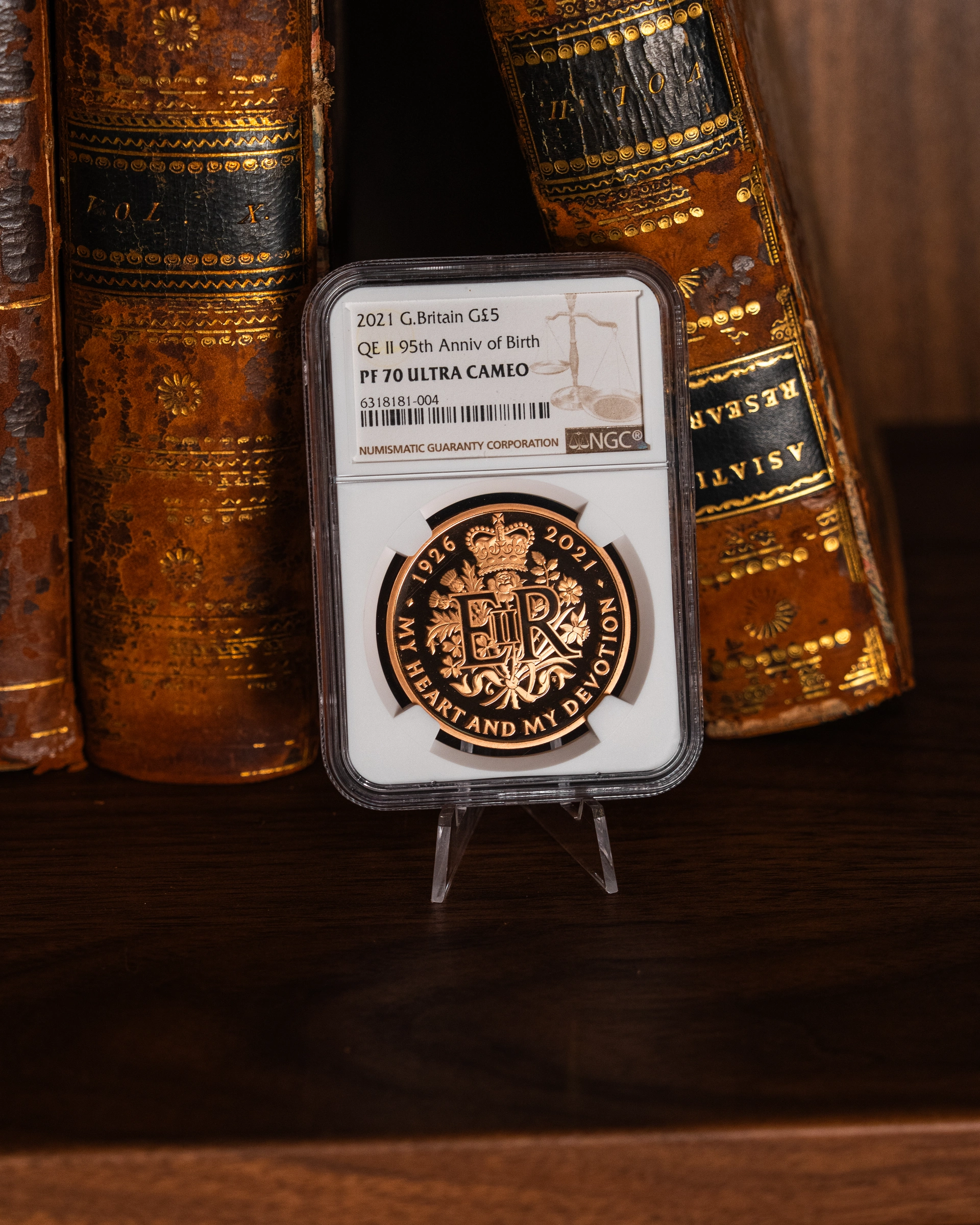 Encapsulated gold coin displayed beside antique books