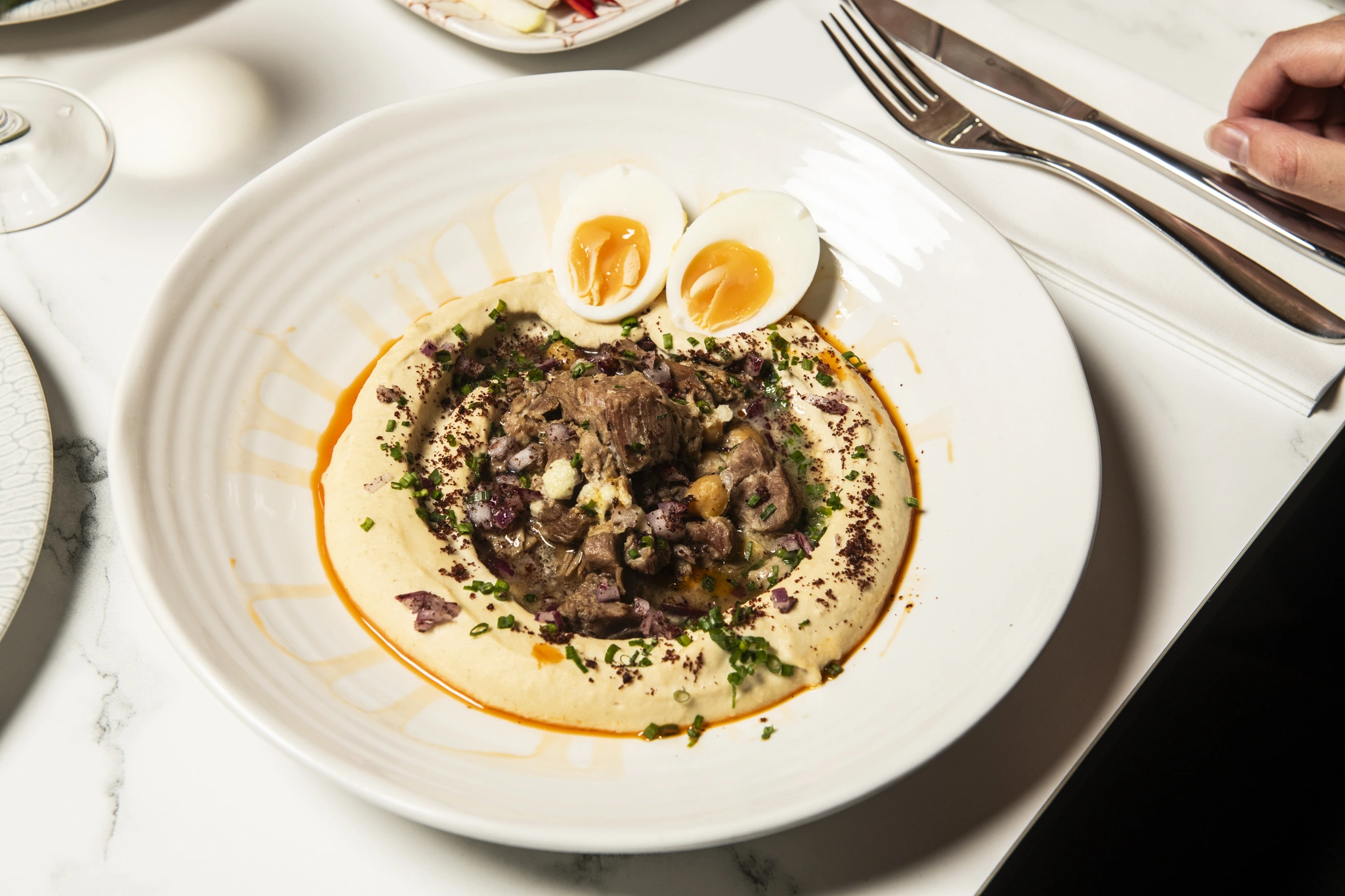 Pukush hummus topped with meat, chickpeas, herbs and soft-boiled eggs